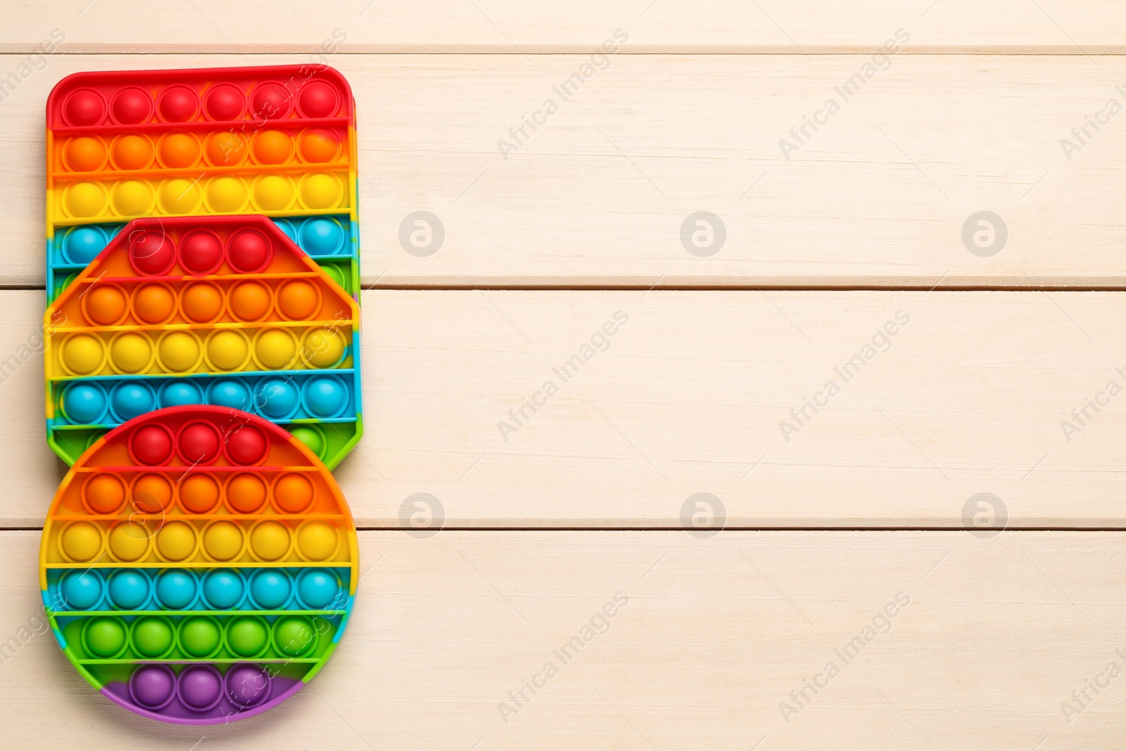 Photo of Rainbow pop it fidget toys on white wooden table, flat lay. Space for text