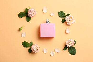 Photo of Beautiful composition with bottle of perfume and roses on color background, flat lay
