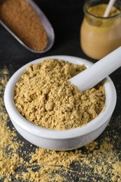 Photo of Mortar with mustard powder on black table