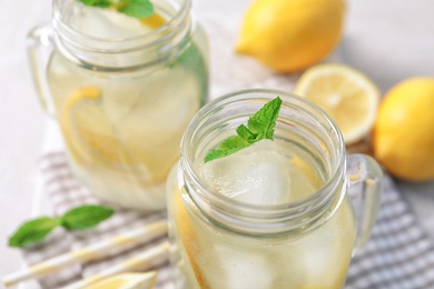Photo of Mason jars of natural lemonade on table, closeup
