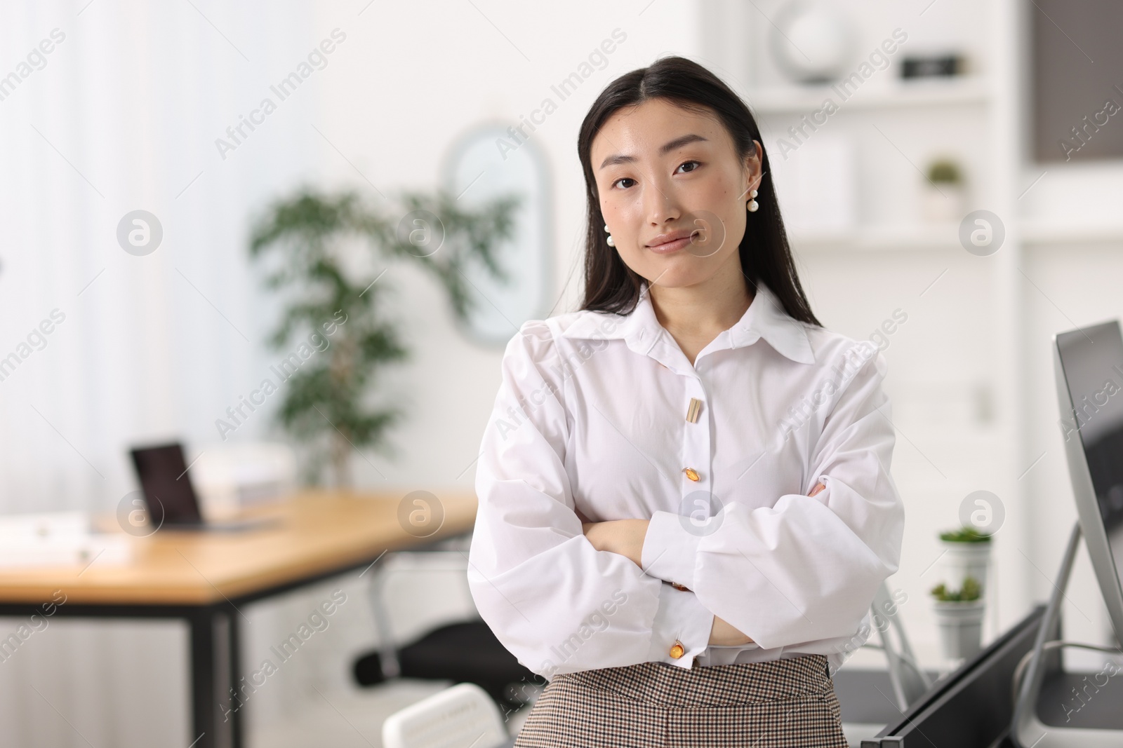 Photo of Portrait of beautiful businesswoman with crossed arms in office. Space for text