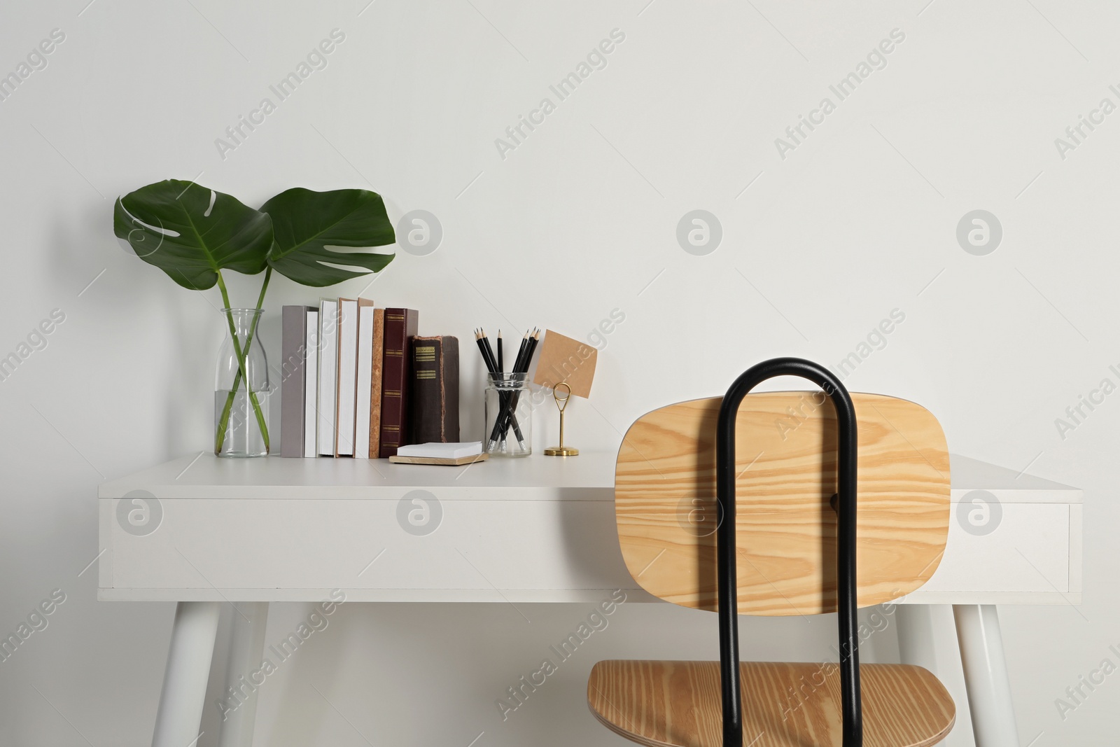 Photo of Comfortable workplace with white desk near wall at home