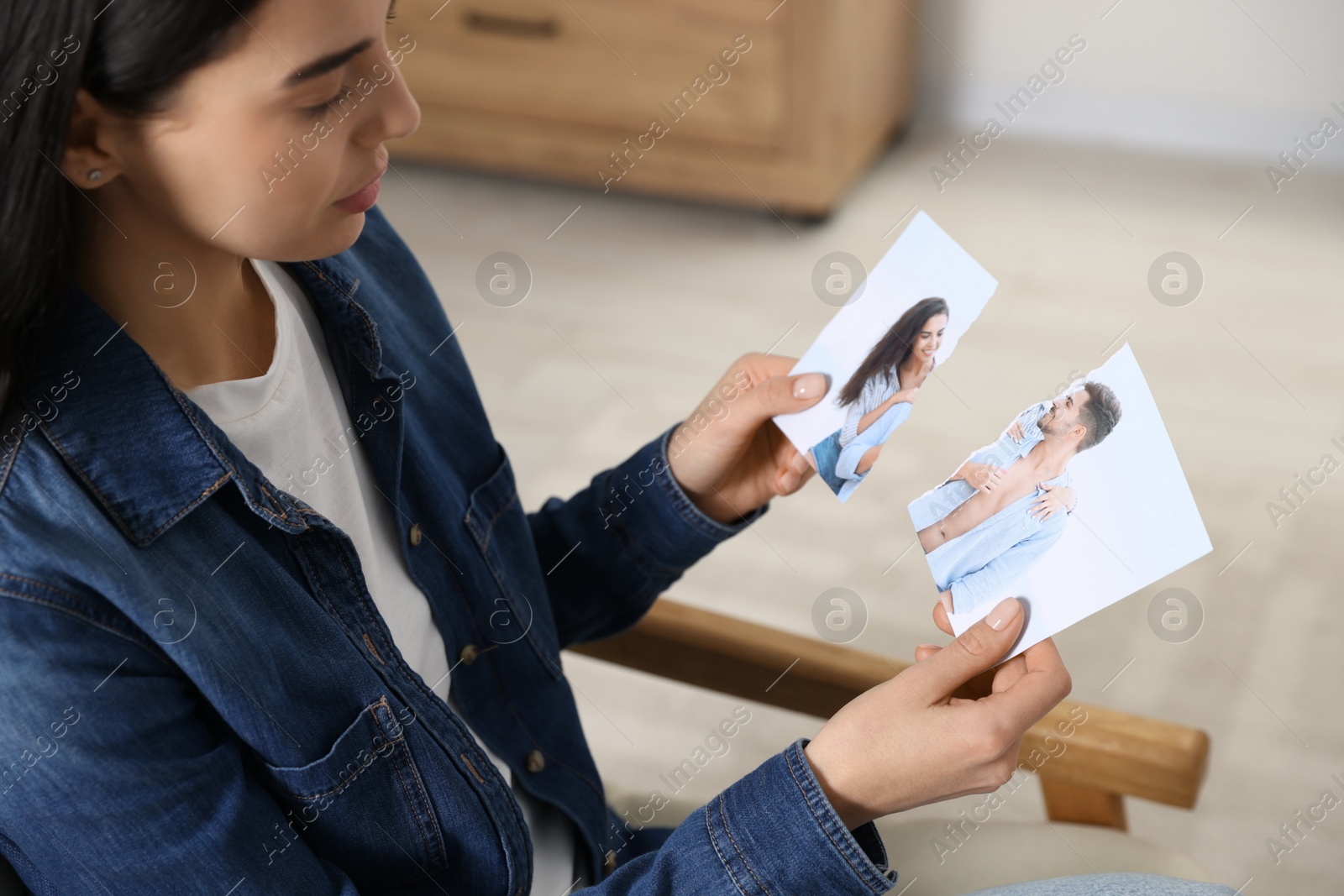 Photo of Woman holding parts of torn photo at home, closeup. Divorce concept