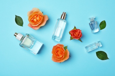 Bottles of perfume and roses on color background, top view