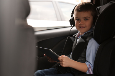 Photo of Cute little boy listening to audiobook in car