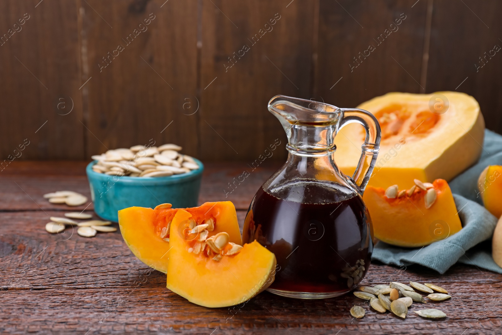 Photo of Fresh pumpkin seed oil in glass jug on wooden table. Space for text