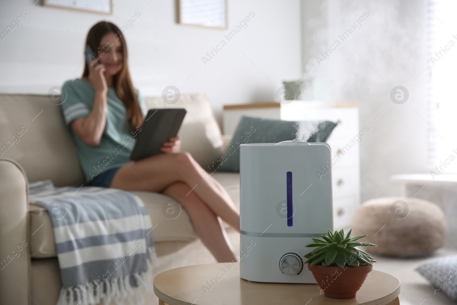 Photo of Modern air humidifier and blurred woman on background