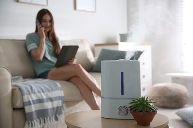 Modern air humidifier and blurred woman on background