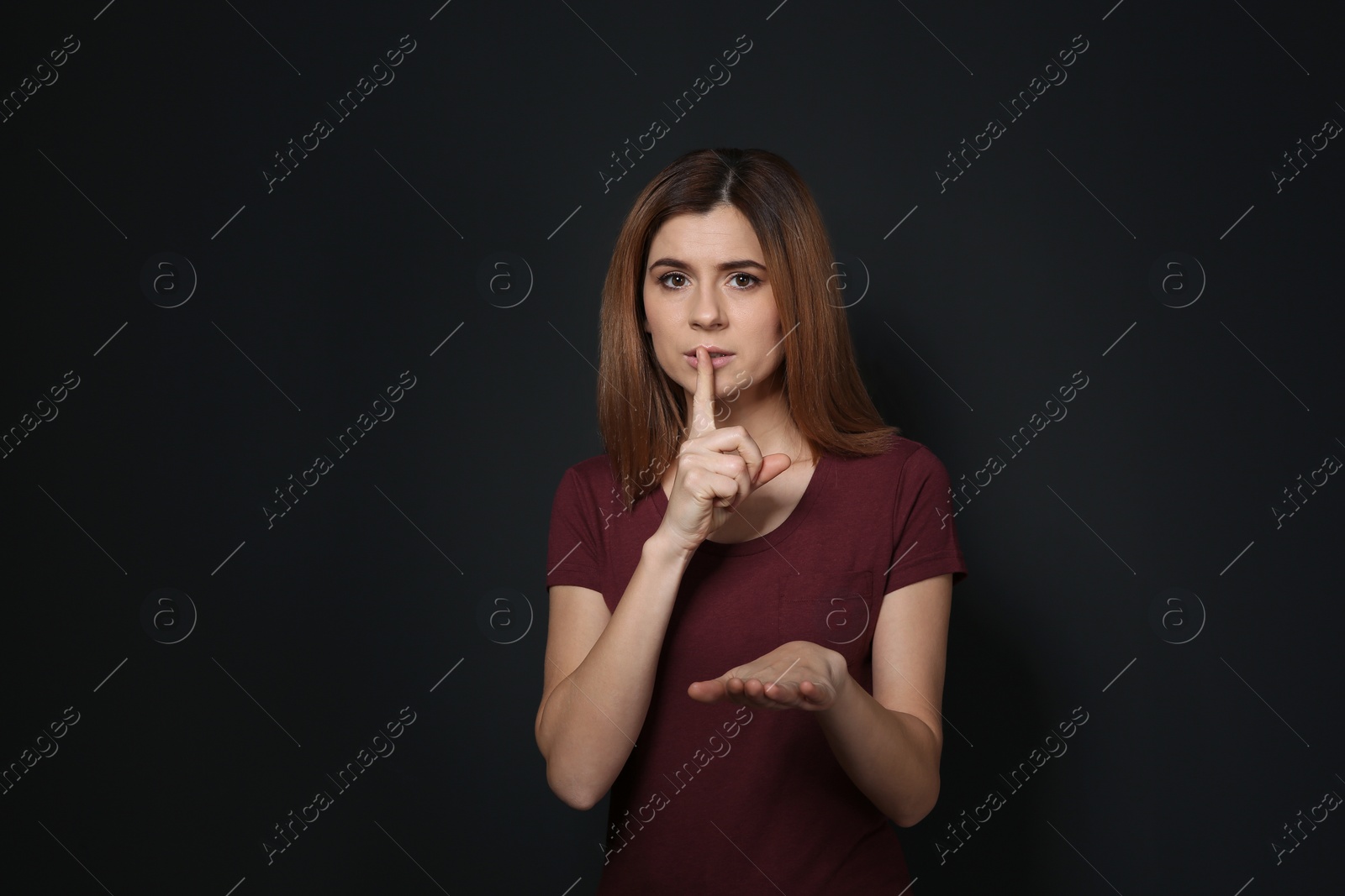 Photo of Woman showing HUSH gesture in sign language on black background