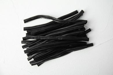Photo of Tasty black liquorice candies on white table, top view