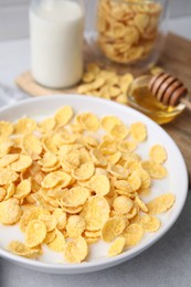 Photo of Breakfast cereal. Corn flakes and milk in bowl on light grey table, closeup