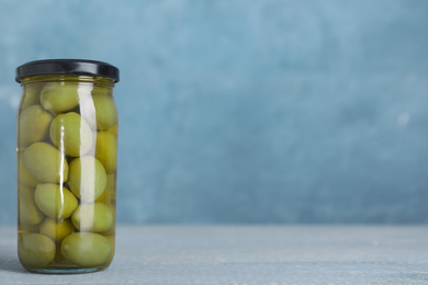 Photo of Glass jar with pickled olives on table. Space for text