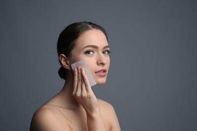 Photo of Beautiful woman using mattifying wipe on grey background