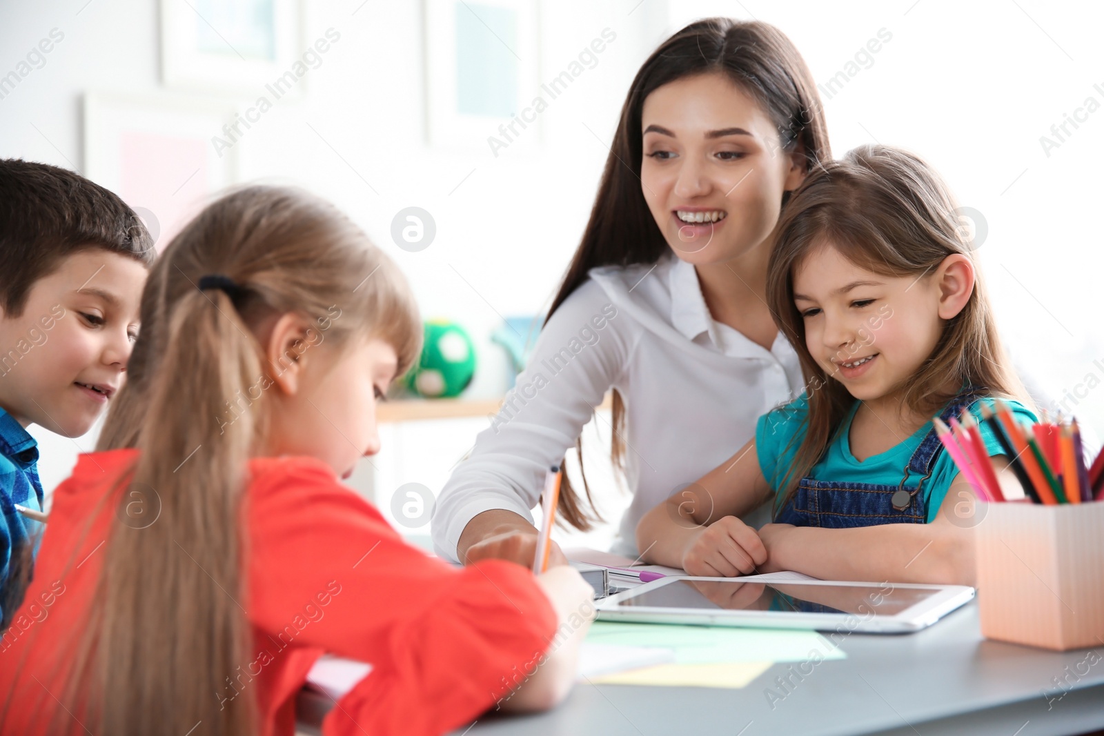 Photo of Female teacher helping girl with her task in classroom at school