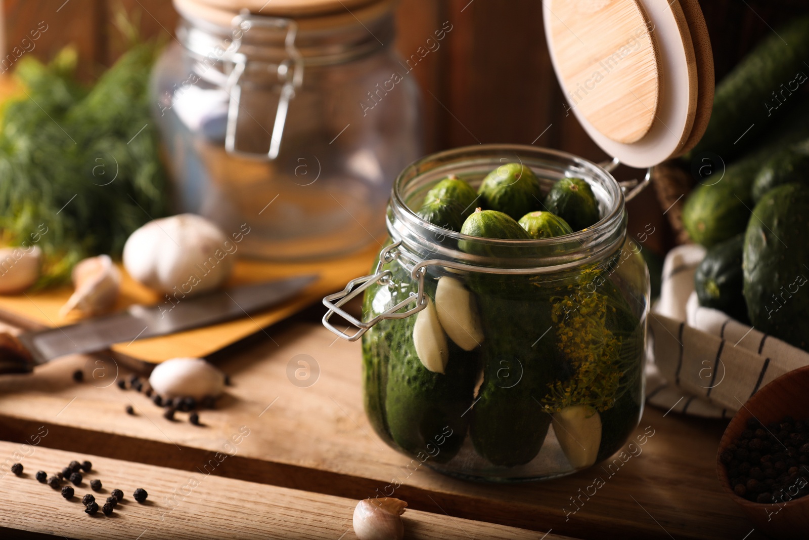 Photo of Glass jar with fresh cucumbers and other ingredients on wooden table. Canning vegetable