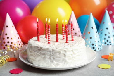 Delicious birthday cake with burning candles on table