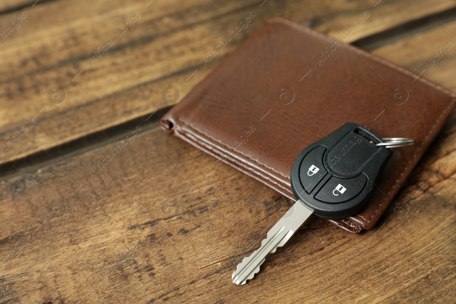 Photo of Car key and leather wallet on wooden background. Space for text