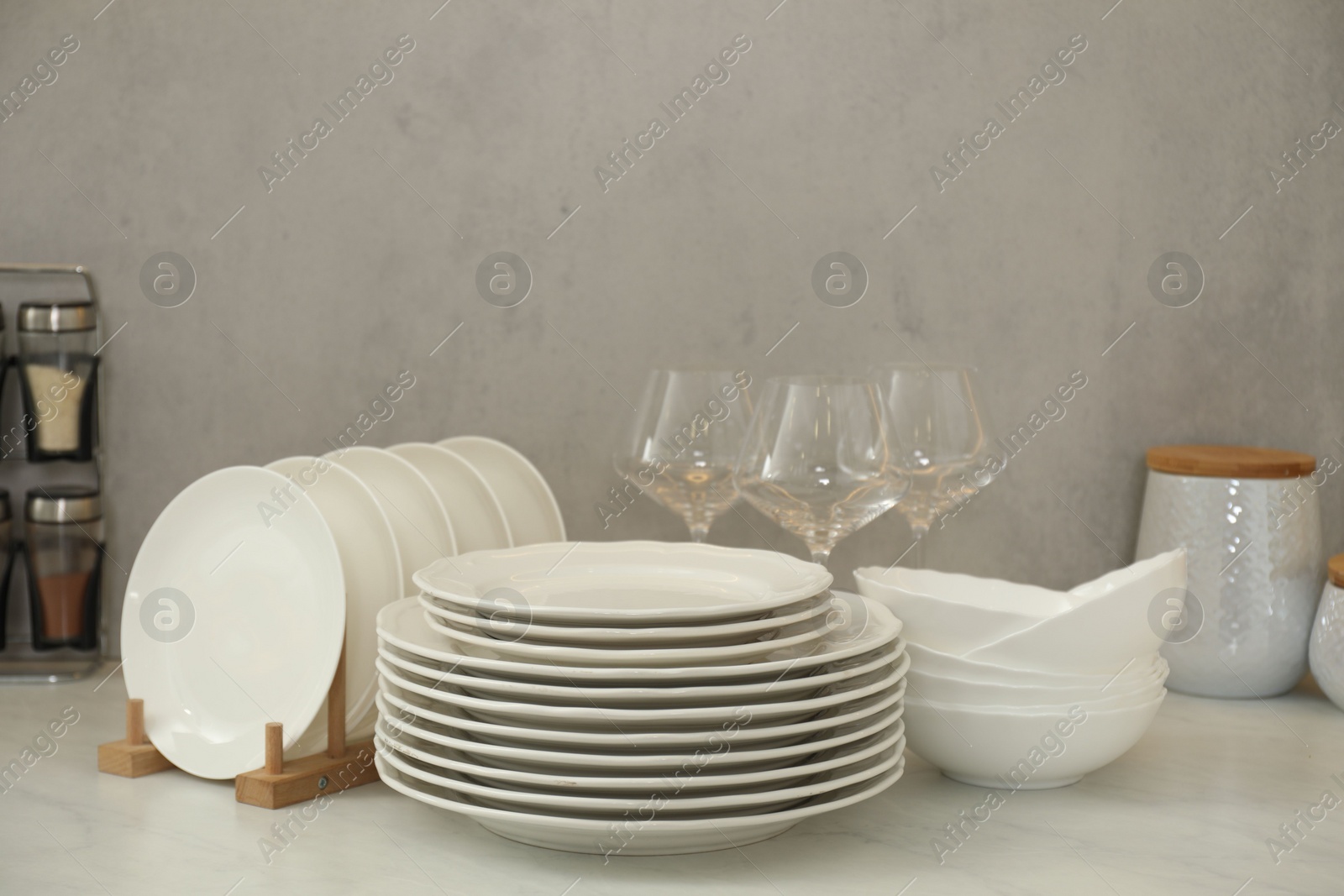 Photo of Clean plates, bowls and glasses on white marble table