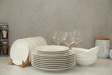 Clean plates, bowls and glasses on white marble table