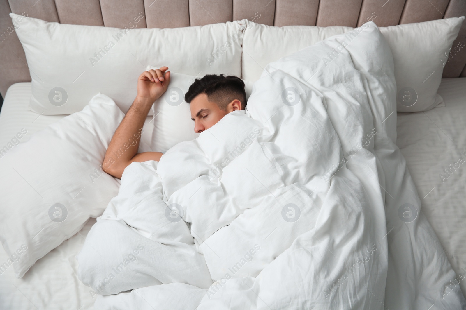 Photo of Handsome man sleeping under soft blanket in bed at home, above view