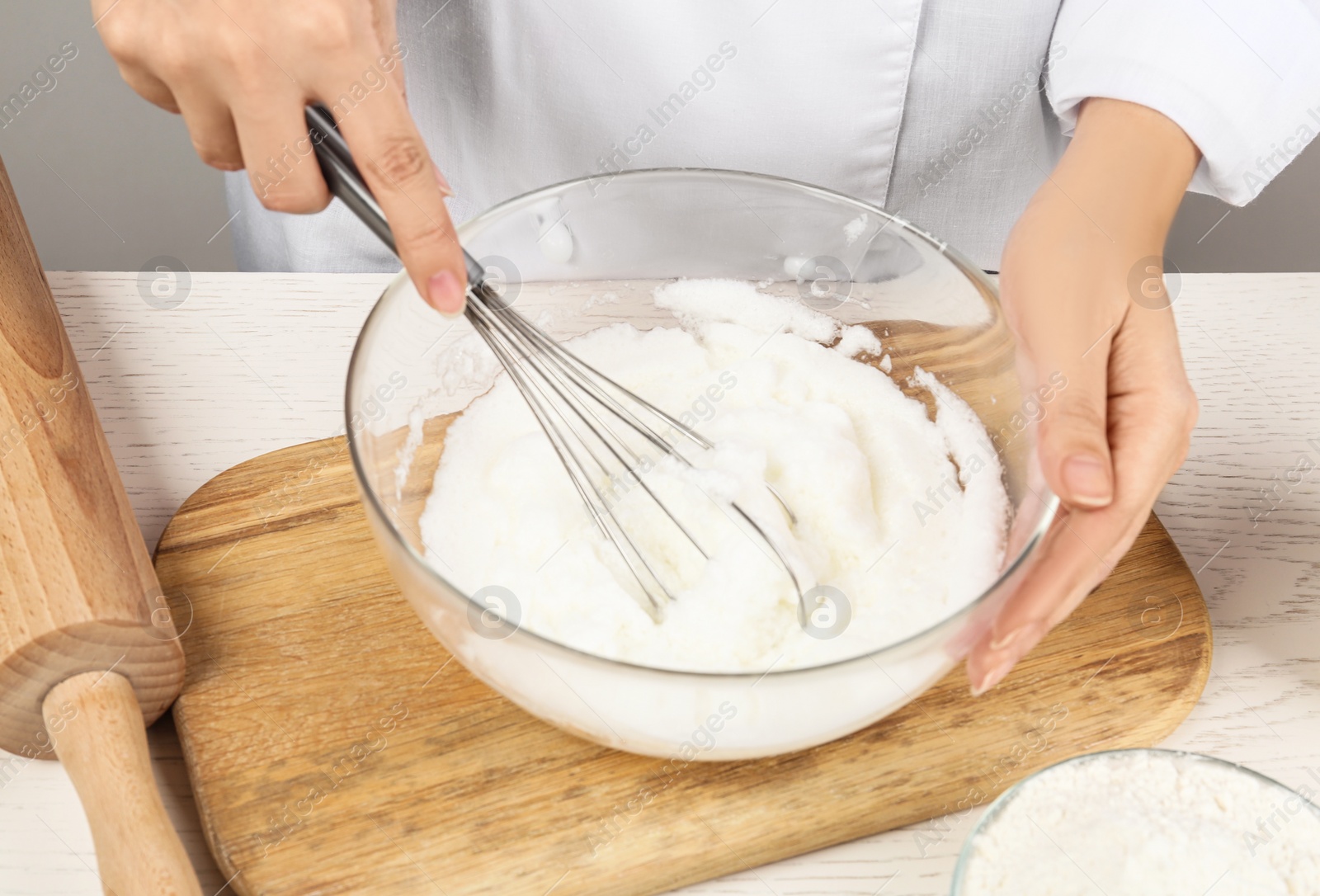 Photo of Woman whipping egg whites at wooden table, closeup. Baking pie