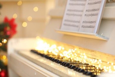 Photo of White piano with festive decor and note sheets indoors, space for text. Christmas music