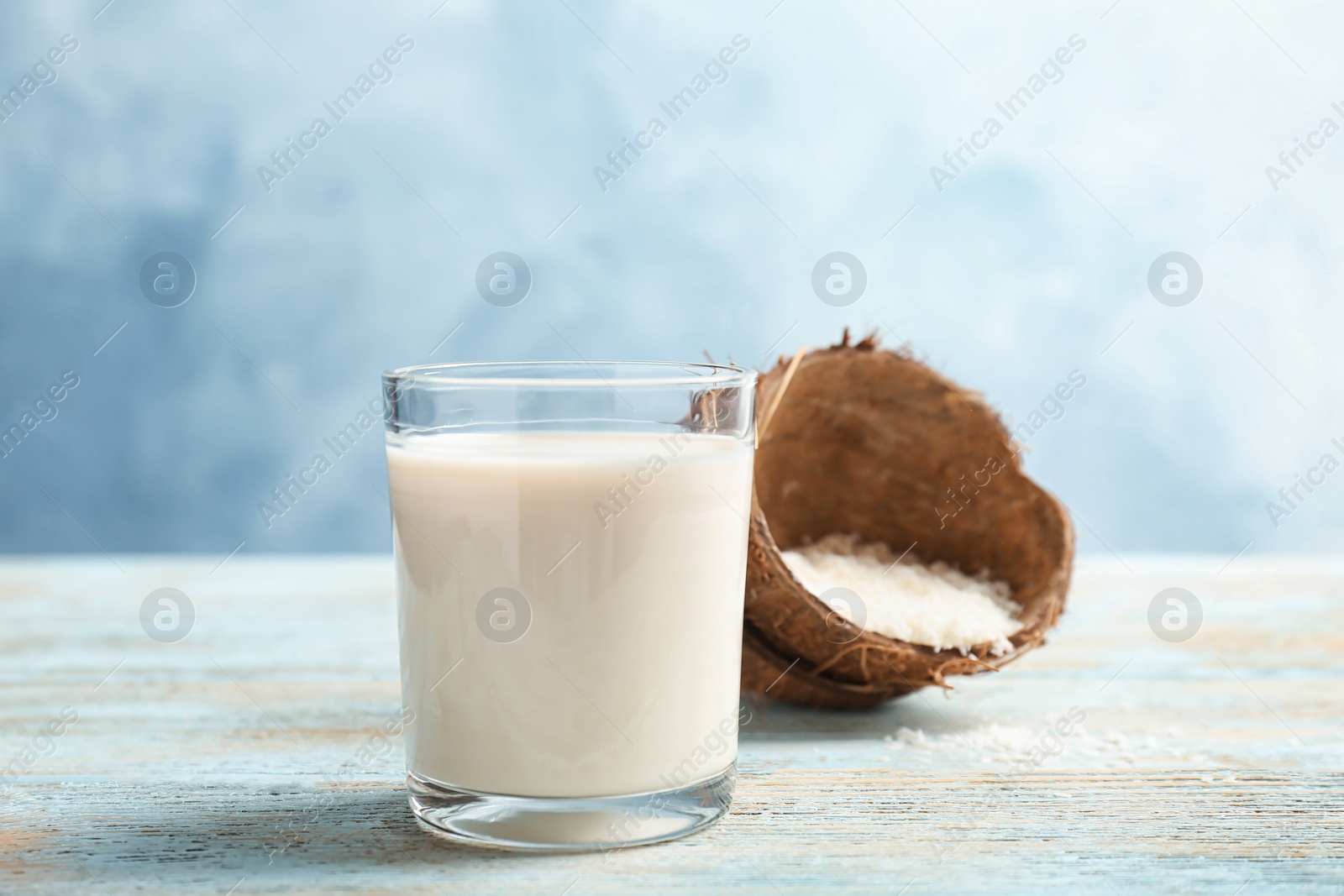 Photo of Glass with coconut milk and flakes on table