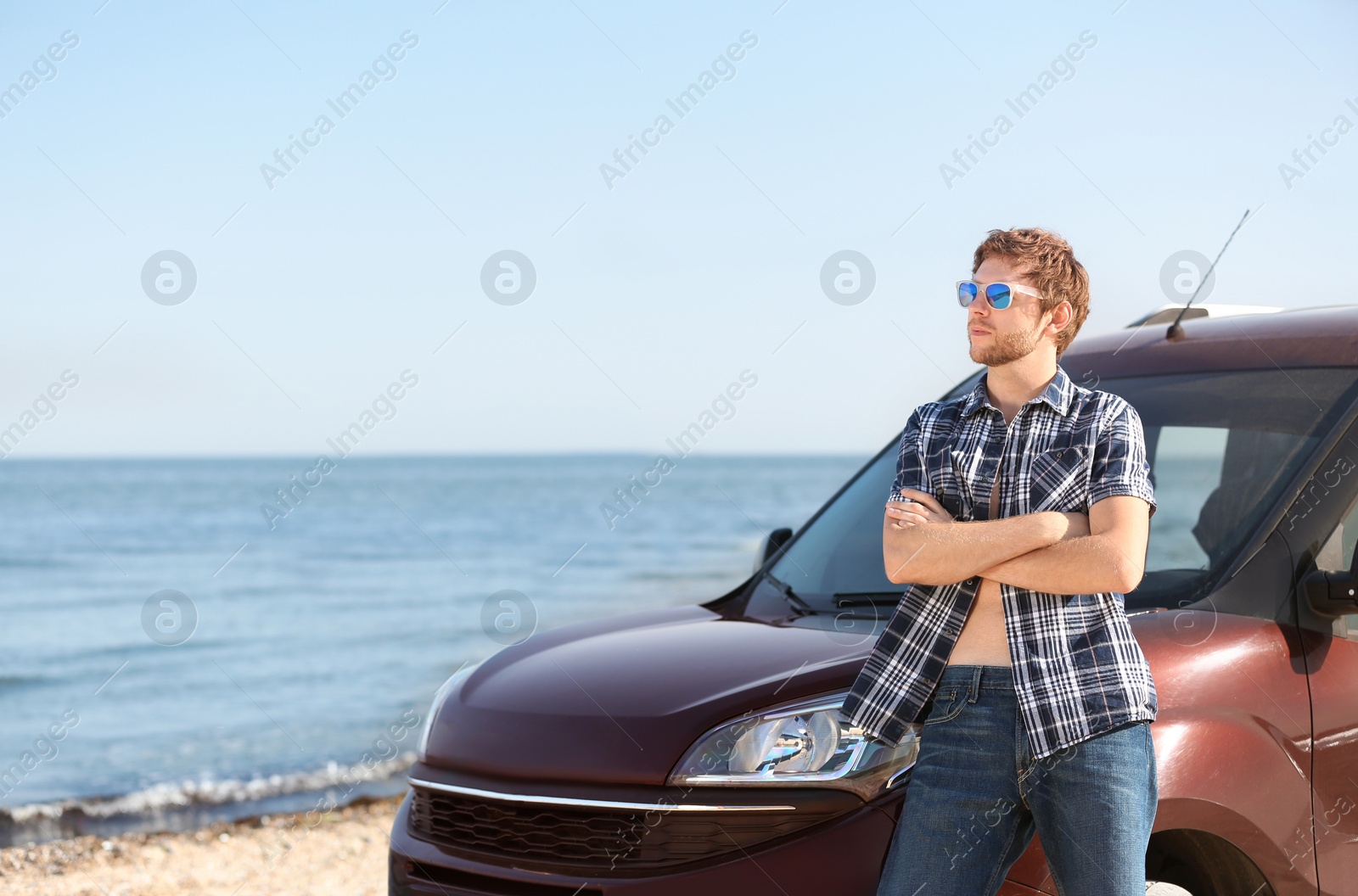 Photo of Young man near car on beach. Space for text