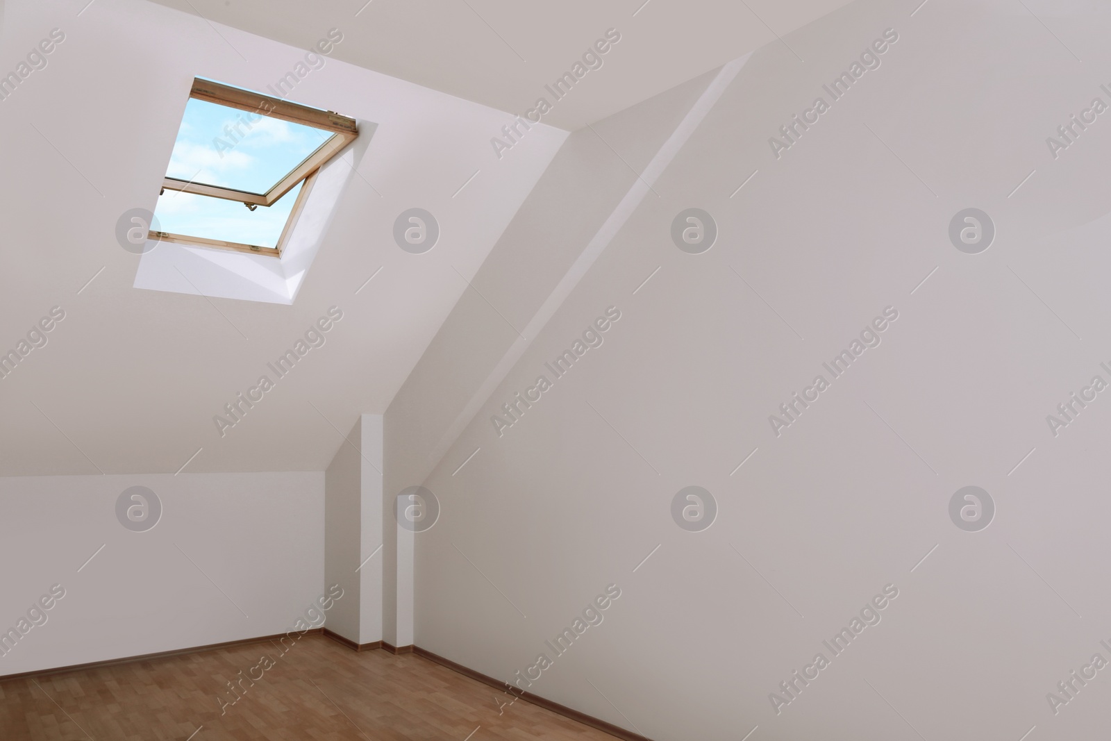 Photo of Light spacious attic room with roof window on slanted ceiling