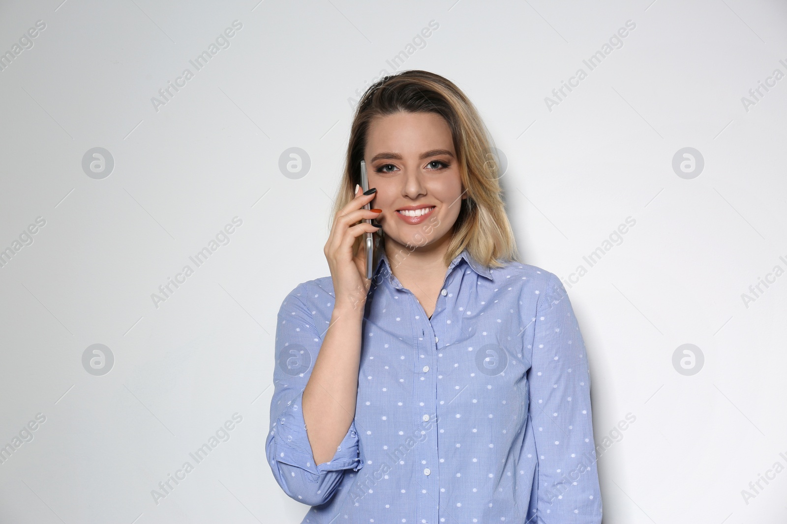 Photo of Portrait of beautiful young woman talking on phone against light background