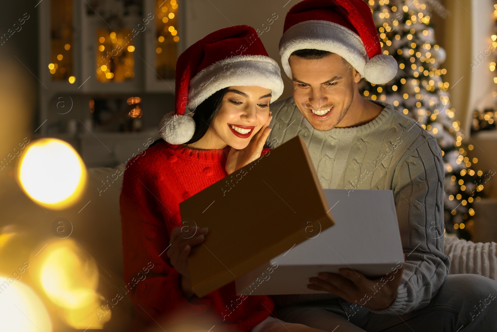 Photo of Happy couple opening magic gift box at home. Christmas celebration