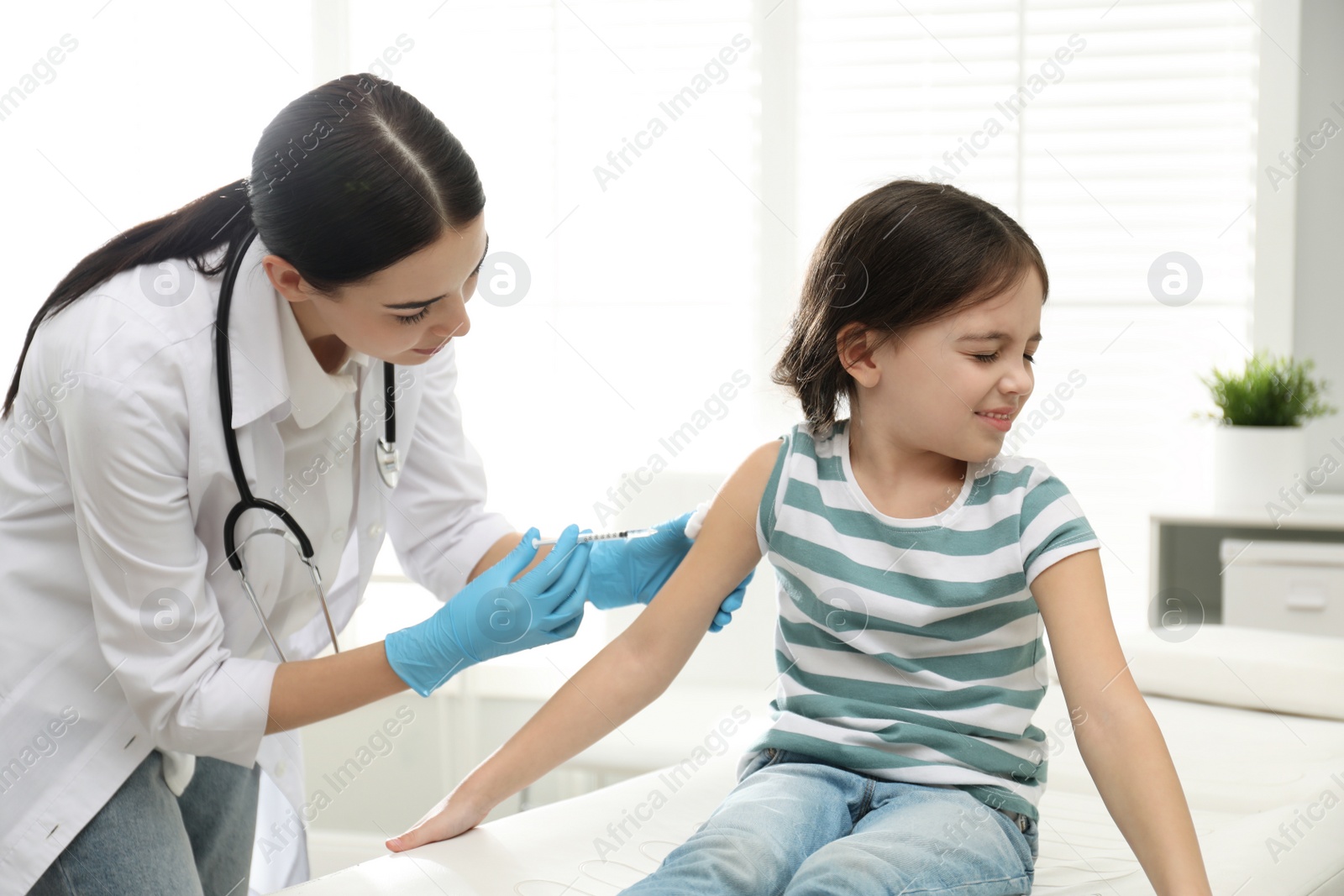 Photo of Doctor vaccinating little child in modern clinic