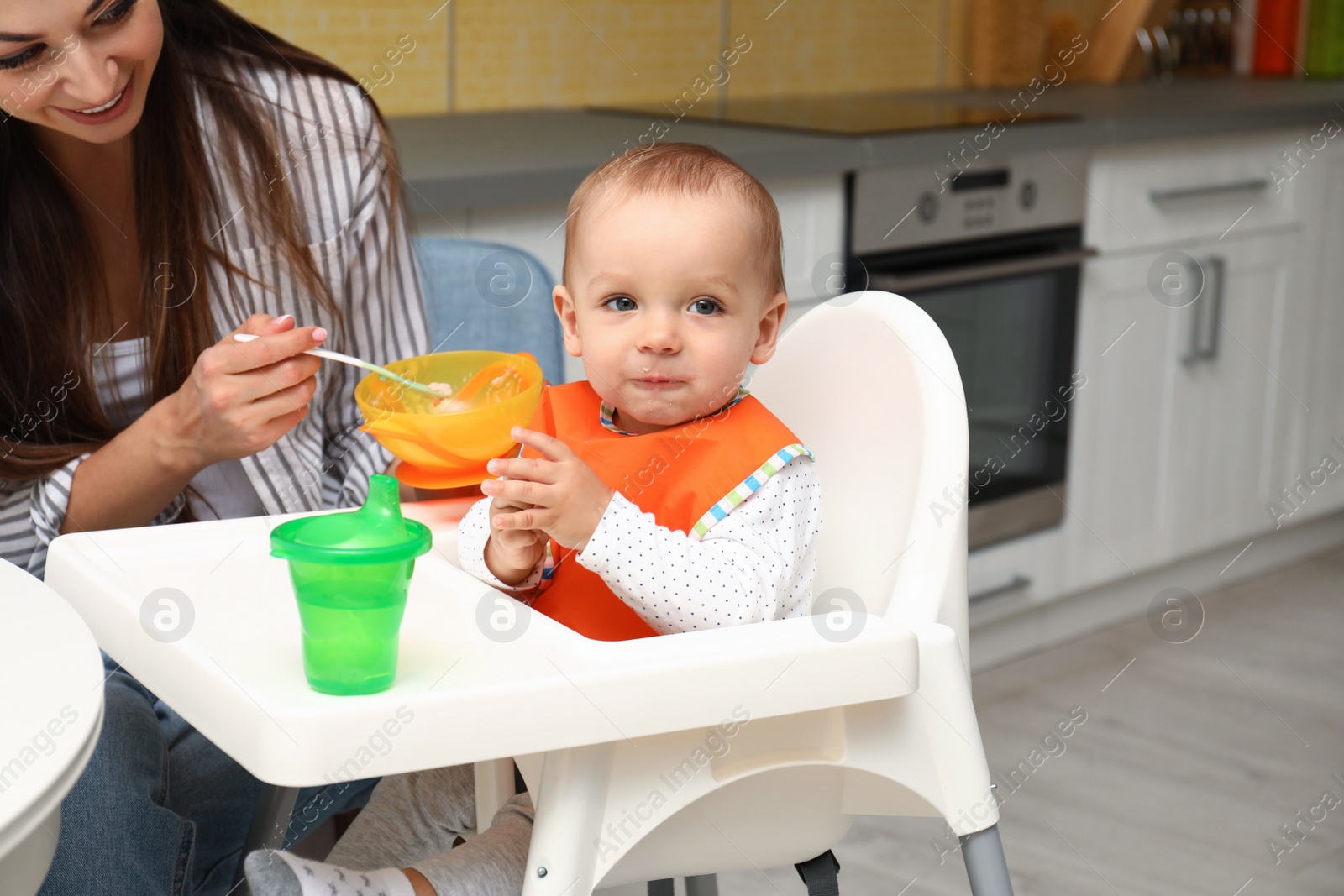 Photo of Young mother feeding her little baby at home