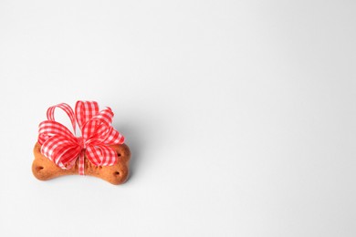 Photo of Bone shaped dog cookie with bow on white background, above view. Space for text
