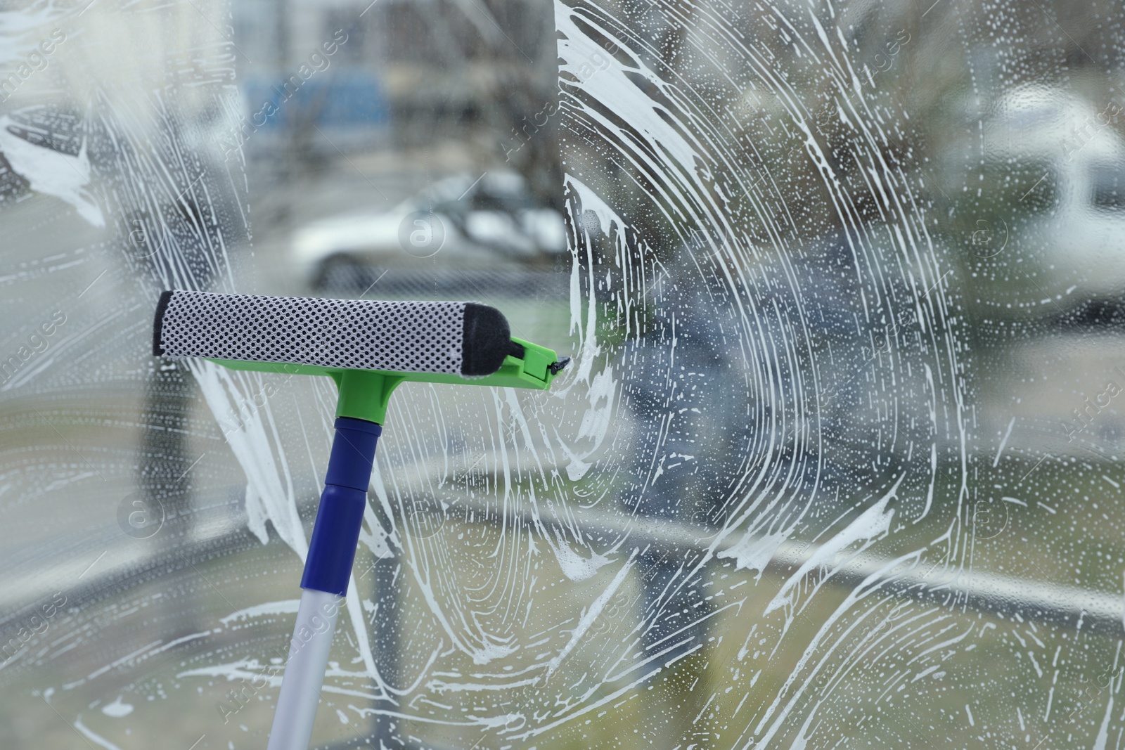 Photo of Cleaning window with squeegee indoors. Space for text