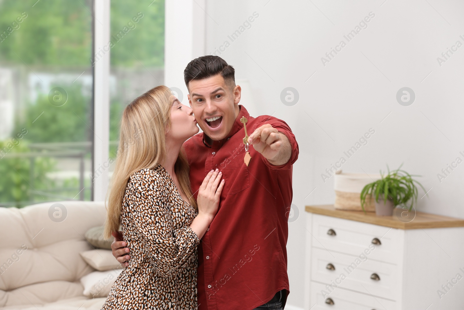 Photo of Happy couple with key from their new house indoors