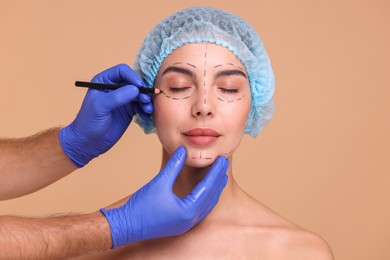 Photo of Doctor drawing marks on woman's face for cosmetic surgery operation against beige background