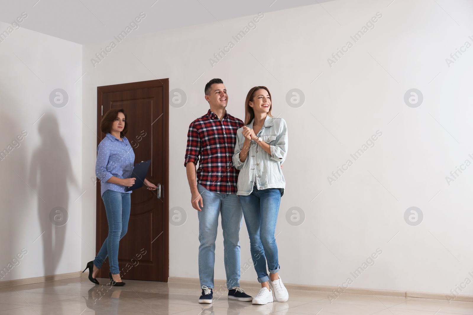 Photo of Real estate agent showing new apartment to young couple. Space for text