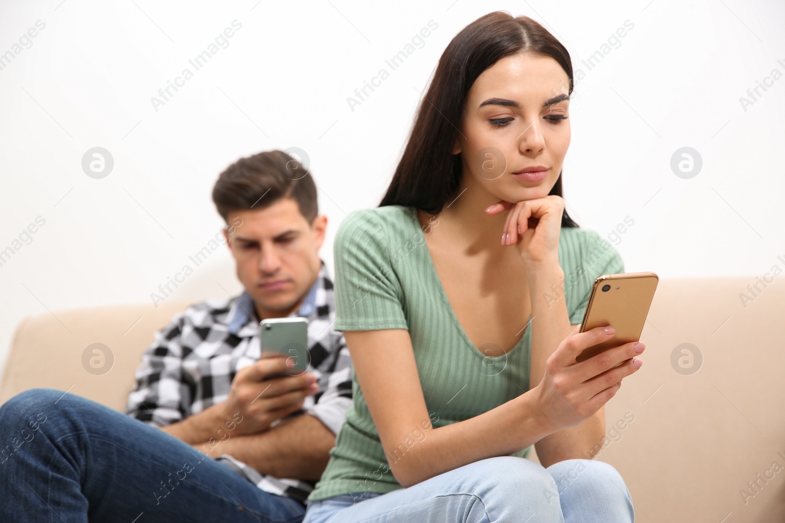 Photo of Couple addicted to smartphones ignoring each other at home. Relationship problems