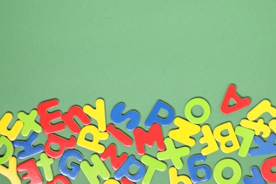 Learning alphabet. Magnetic letters on green background, flat lay. Space for text