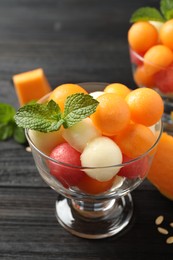 Photo of Melon and watermelon balls with mint in dessert bowl on black wooden table