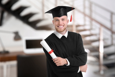 Image of Happy student with graduation hat and diploma in office