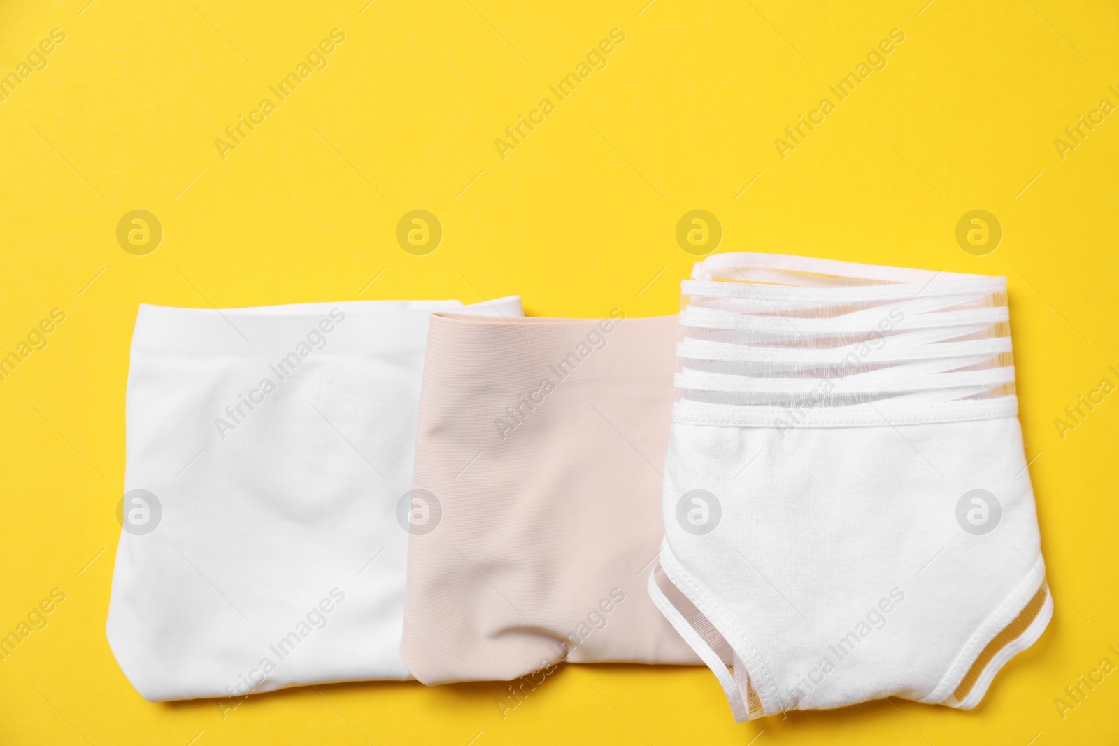 Photo of Stylish folded women's underwear on yellow background, flat lay. Space for text