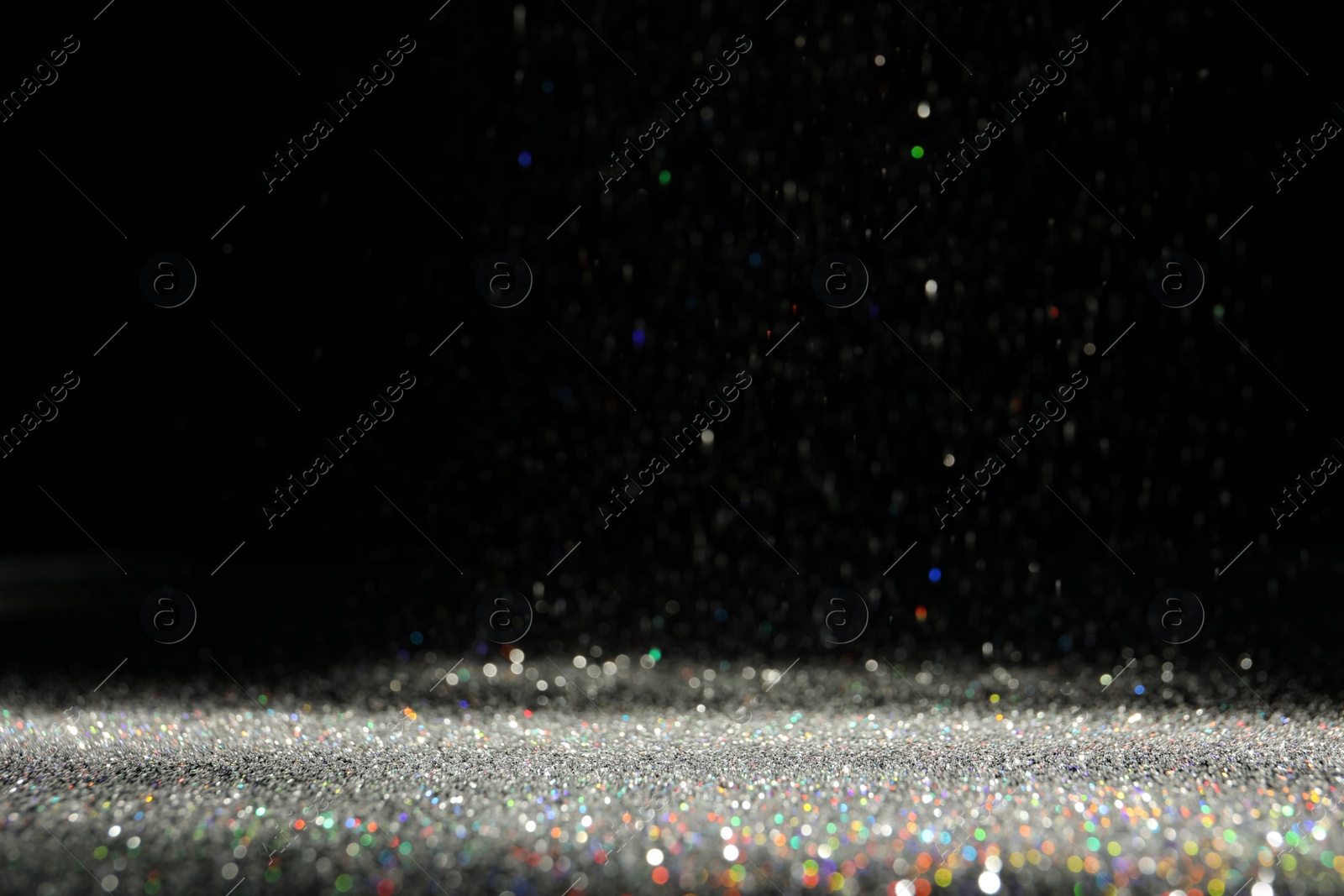 Photo of Shiny colorful glitter falling down on black background. Bokeh effect