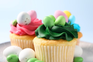 Tasty cupcakes with Easter decor on light blue background, closeup