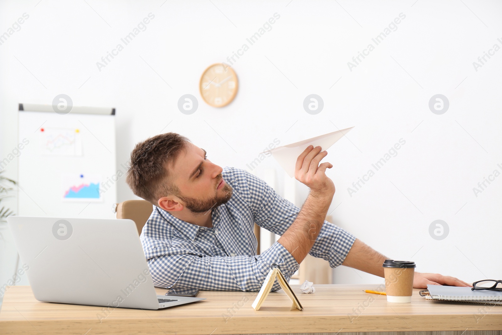 Photo of Lazy office employee playing with paper plane at workplace
