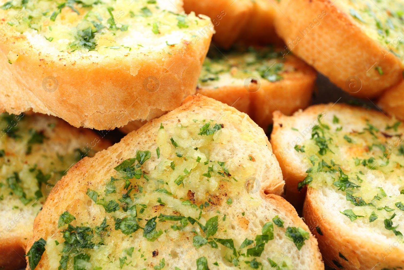 Photo of Slices of toasted bread with garlic and herbs as background, closeup