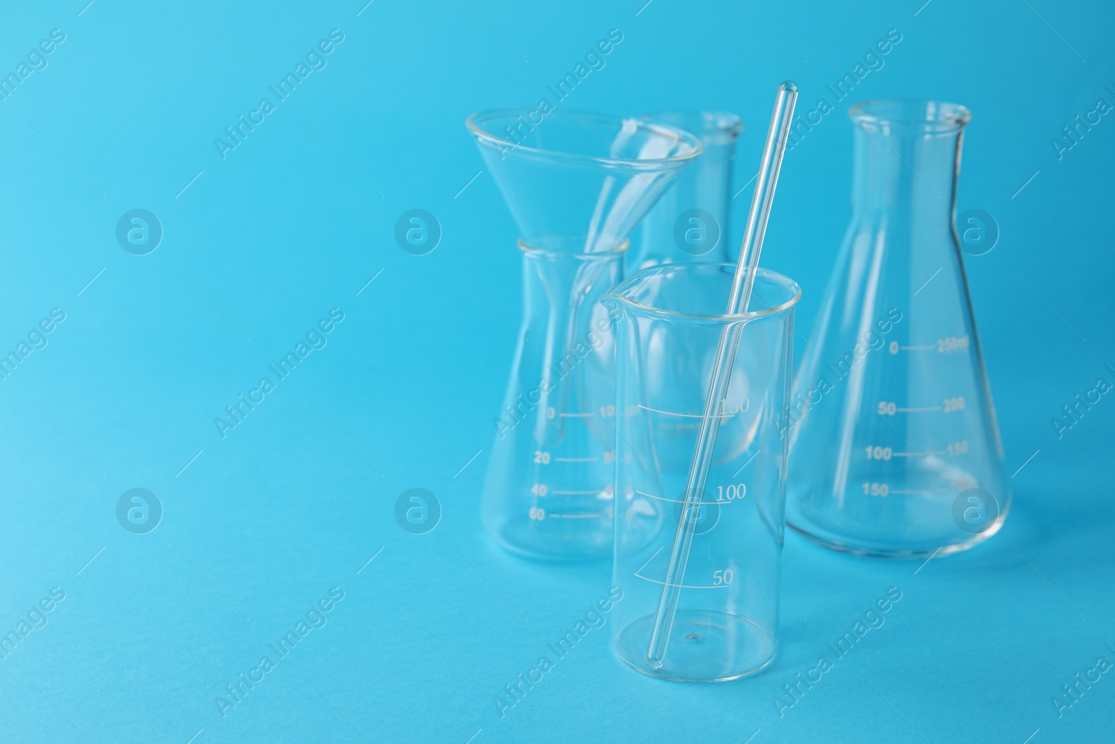 Photo of Different laboratory glassware on light blue background. Space for text