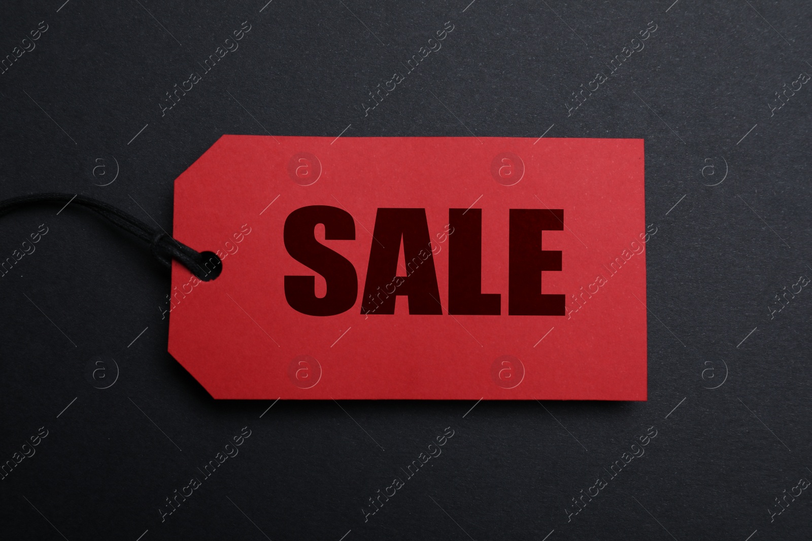 Photo of Red tag with word Sale on dark background, top view. Black Friday