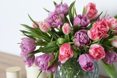 Photo of Beautiful bouquet of colorful tulip flowers near white wall, closeup